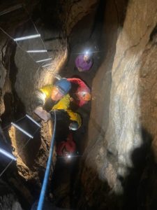 Un petit groupe descend avec une échelle dans l'Aven des Côtes. Parcours Spéléo Aventure de la Base Canyon de la Besorgues.