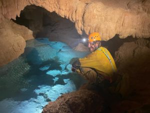 Spéléo Aventure avec rappel. Un participant assis au bord de la rivière souterraine . Au coeur du massif calcaire du sud Ardèche, l’Aven des Côtes permet d’accéder à une rivière souterraine et de grandes salles.