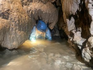 UNe petite fille qui rampe dans la Grotte des Croix Blanches. Parcours spéléo famille à Vinezac